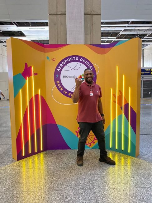 Painel cenográfico colorido com led amarelo e funcionário posando no Aeroporto Rio Galeão