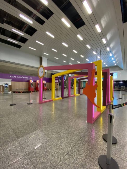 Portal cenográfico do Rock in Rio visto ao fundo do saguão do aeroporto