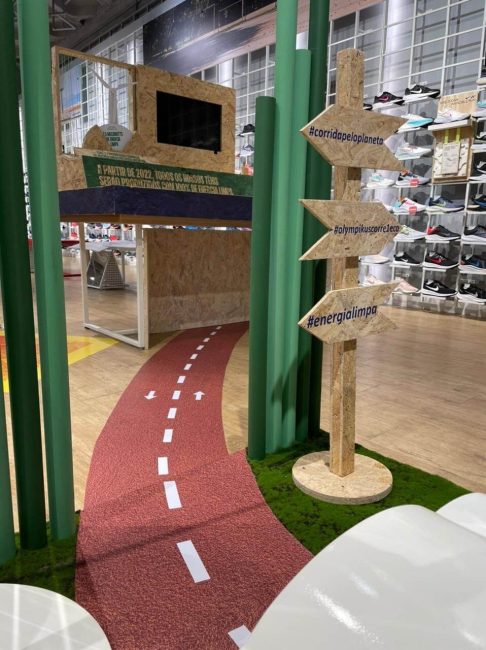 Detalhe da pista vermelha e das placas direcionais da cenografia Olympikus no ponto de venda