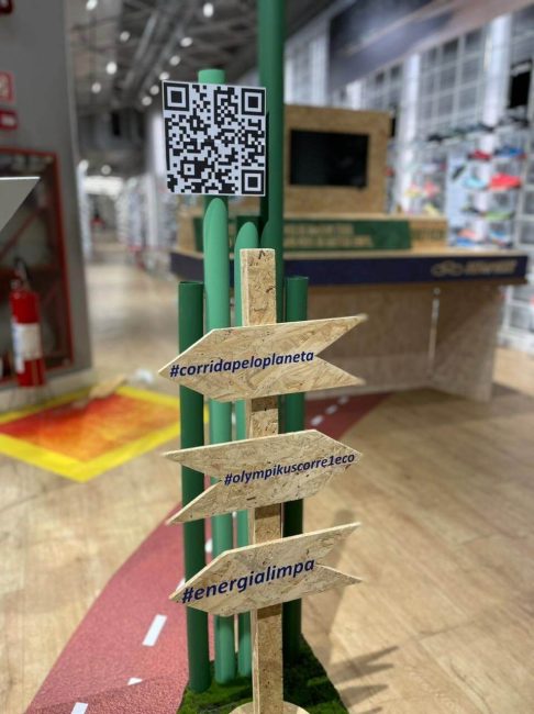 Placas direcionais de madeira com QR code na cenografia Olympikus
