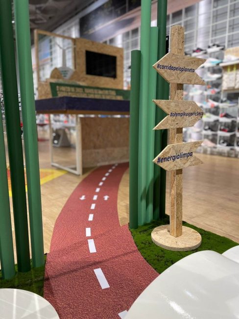 Cenografia Olympikus com pista vermelha, hastes verdes e totem de placas