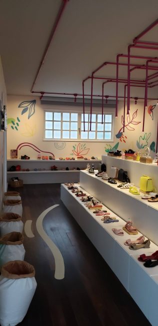 Loja pop-up Melissa Remake na Galeria 664: bancada branca com sapatos e vaso, vista lateral