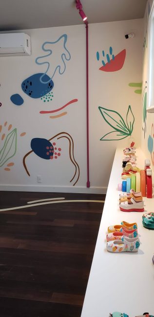 Parede com grafismos coloridos e bancada de sapatos Melissa na pop-up da Galeria 664