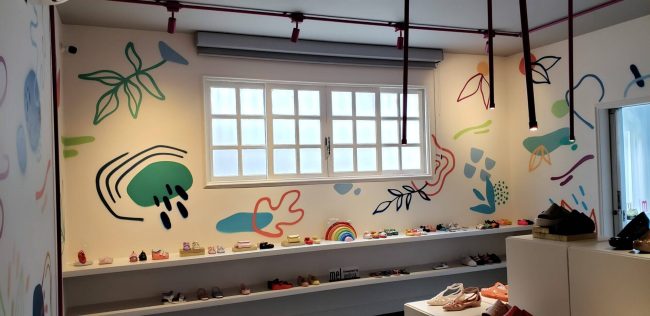 Loja pop-up Melissa Remake na Galeria 664: parede pintada com folhagens e grafismos ao longo da bancada