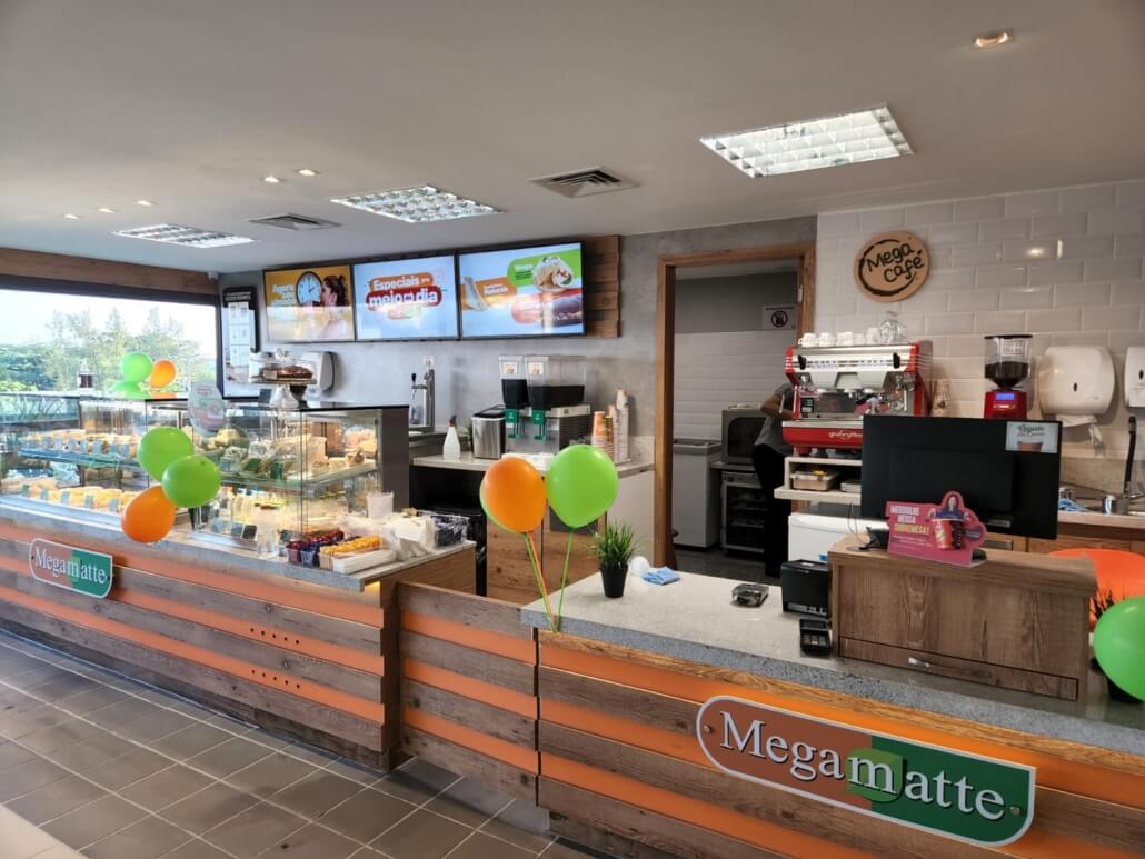 Balcão de atendimento da loja Megamatte com letreiro verde e revestimento de madeira