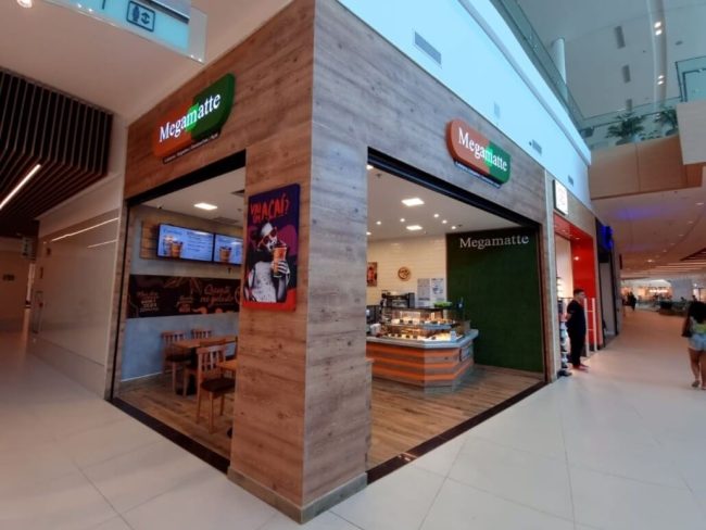 Fachada da loja Megamatte em shopping, com painéis de madeira e letreiro iluminado