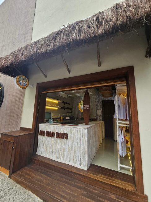 Fachada e balcão do bar Zaga Bowls com janela de atendimento e deck de madeira