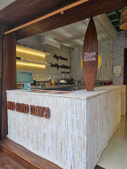 Balcão de atendimento do Zaga Bowls com prancha de surfe decorativa e luz embutida