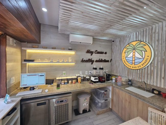 Bancada de preparo do Zaga Bowls com letreiro "Stay Cacau & healthy" e forro de madeira