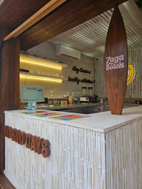 Balcão do bar Zaga Bowls com prancha de surfe e revestimento em madeira clara