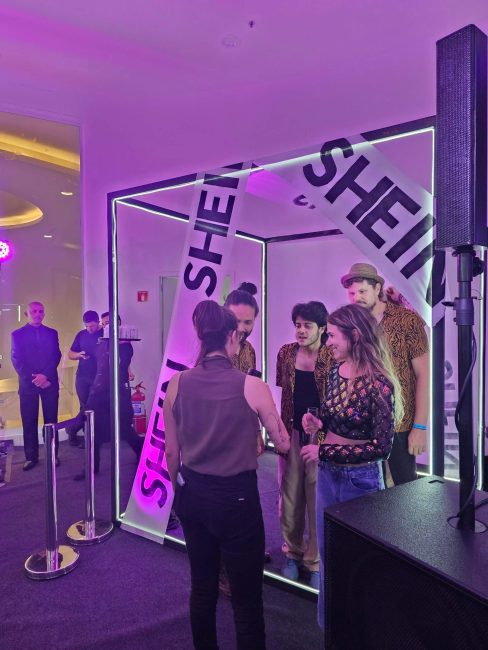 Cubo com fitas Shein e visitantes interagindo na pop-up