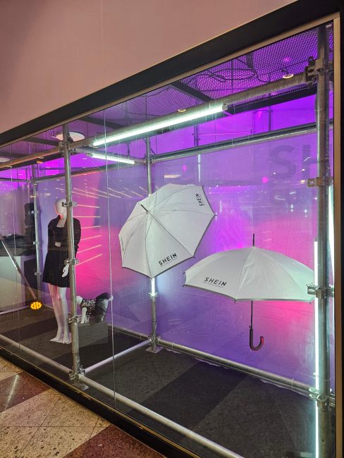 Vitrine de vidro com guarda-chuvas brancos e iluminação led na pop-up Shein