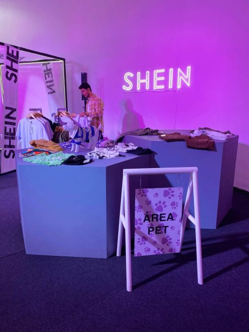 Mesa expositora azul e logo Shein luminoso na parede