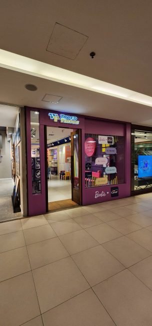 Entrada da loja Coral com vitrine cenográfica em corredor de shopping