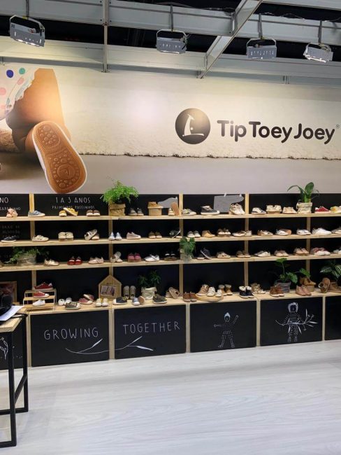 Stand Tip Toey Joey na Feira Ópera: parede de prateleiras de madeira com letreiro Tip Toey Joey