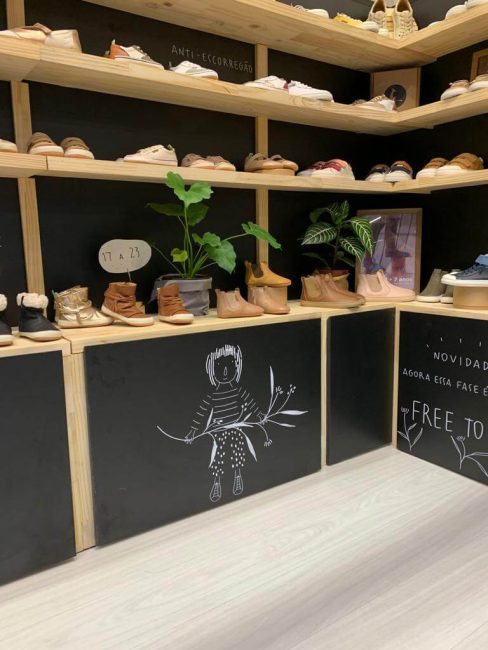Stand Tip Toey Joey na Feira Ópera: cantos com prateleiras de sapatos e plantas, com a frase "growing together"