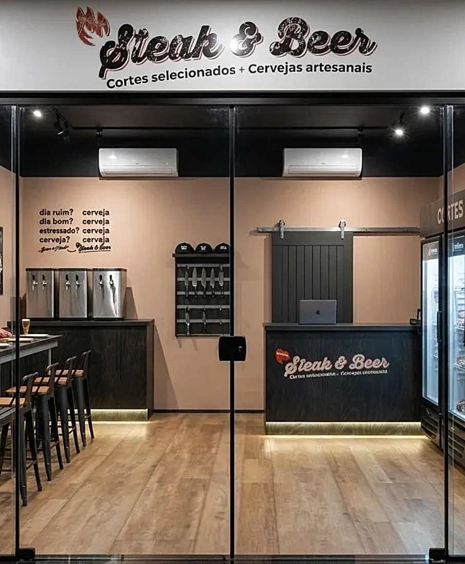Fachada da loja Steak & Beer com letreiro, balcão, chopeiras e piso de madeira, projeto da Unpack Design