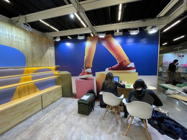 Stand Tip Toey Joey na Feira Ópera – parede azul com sapatos em destaque